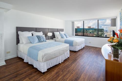 une chambre avec deux lits et une grande fenêtre dans l'établissement Waikiki Penthouse @ The Monarch Hotel, à Honolulu