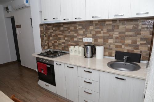 a kitchen counter with a sink and a stove at Robert 's apartament in Ploieşti