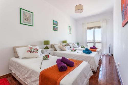 two beds in a white room with purple pillows on them at Sea View Fairy Tale in Faro