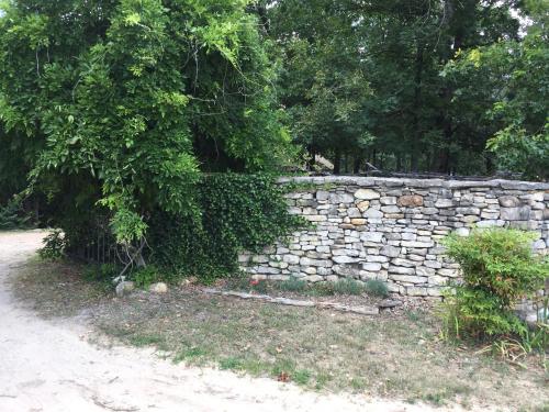 un mur en pierre à côté d'un chemin de terre dans l'établissement Cherokee Mountain log Cabins, à Eureka Springs