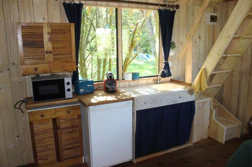 - une cuisine dans une cabine avec un four micro-ondes et une fenêtre dans l'établissement Le chalet de la Ferme Feugère, à Barbeville