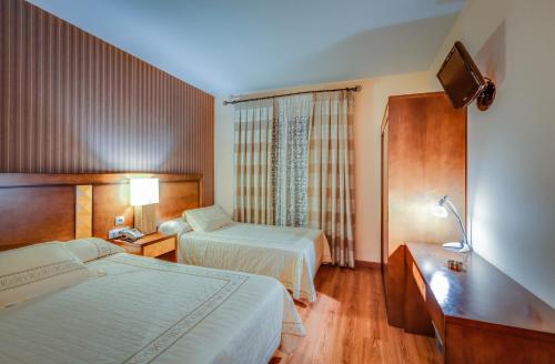 a hotel room with two beds and a television at Hotel Ciudad de Martos in Martos