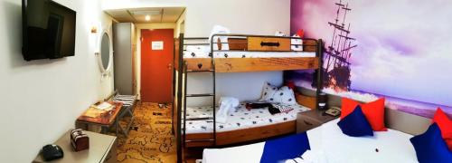 a room with two bunk beds and a tv at Pirates Resort in Mamaia