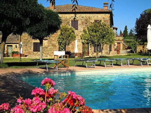 une piscine en face d'un bâtiment avec des bancs et des fleurs dans l'établissement Agriturismo Casalpiano, à Pienza