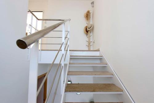 a staircase in a house with white walls and a metal rail at Can Lou-Casa con Caracter en Cullera in Faro de Cullera