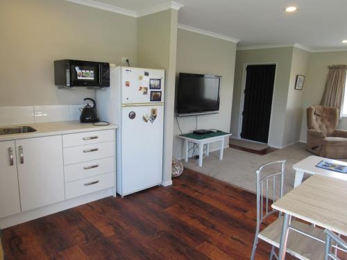 a kitchen with a white refrigerator and a table with chairs at The Practice Fairway in Tauranga