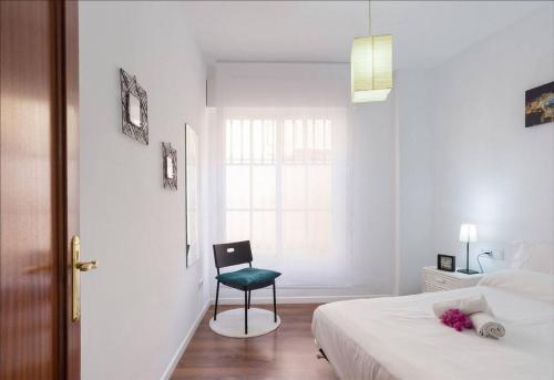 a bedroom with a chair and a bed and a window at Perla Lagunillas Málaga in Málaga