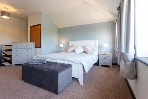 a bedroom with a white bed with a ottoman in it at The Windmill Cottage in Melton Mowbray