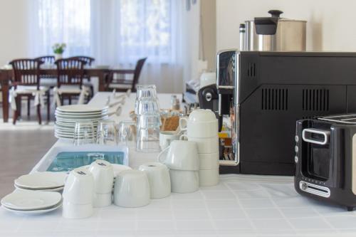 a table with white cups and plates and a microwave at Villa Anzio in Mariánské Lázně
