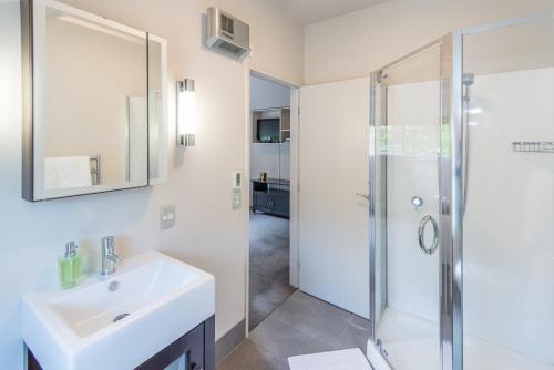 a white bathroom with a sink and a shower at Lakeside Luxury with Spa in Queenstown