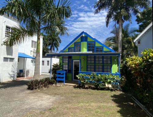 a blue and green house with palm trees in front at Blue House Joyuda in Cabo Rojo