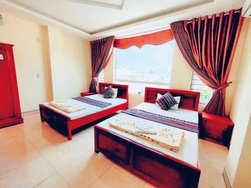 twee bedden in een kamer met een raam bij Hoang Kim Ha Giang Hotel in Ha Giang