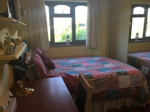 a bedroom with a bed and a table and windows at The Cedars House B&B in Nuneaton