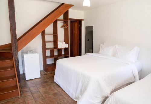 a bedroom with two white beds and a staircase at Trancoso Pousada in Trancoso