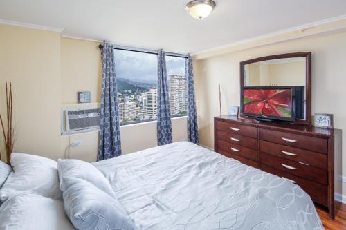 a bedroom with a bed and a tv and a window at 2 Bedroom Corner Suite & Tropical Views in Honolulu