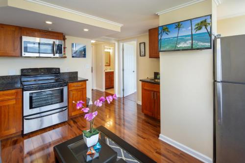 a kitchen with a refrigerator and a table with flowers at 2 Bedroom Corner Suite & Tropical Views in Honolulu