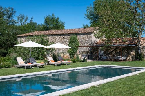 une piscine avec chaises et parasols à côté d'un bâtiment dans l'établissement Maison Le Sèpe - Vignoble Bio et Maison d'hôtes, à Sainte-Radegonde