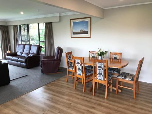 een woonkamer met een tafel en stoelen en een bank bij Waitomo Golf Ridge in Waitomo Caves