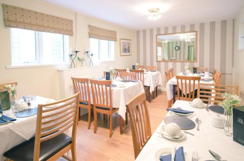 a dining room with white tables and chairs at Ennislare House Guest Accommodation in Bangor