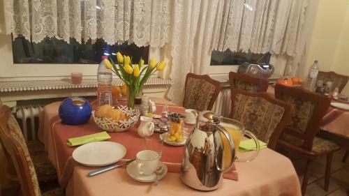 Hotel Heideklause في كولونيا: طاولة طعام مع قماش الطاولة الزهري والزهور