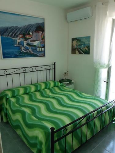 a bedroom with a green bed with a painting on the wall at La casa Verde in Ischia