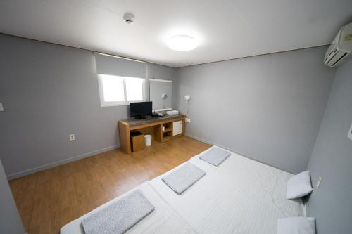 an empty room with two beds and a television at Beewon Guesthouse in Seoul