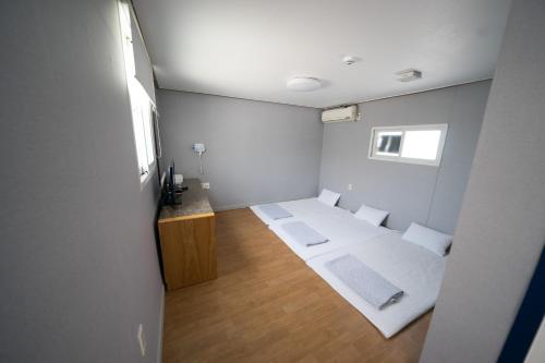 a small room with two beds and a window at Beewon Guesthouse in Seoul