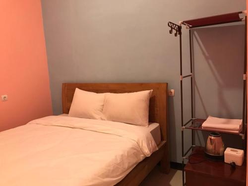 a bed with white sheets and a wooden head board at RoomZ Budget Residence in Semarang