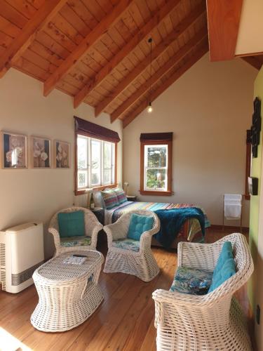 een woonkamer met rieten stoelen en een bank bij The Blackhouse Cottage in Hokitika