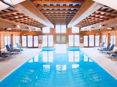 une grande piscine avec des chaises bleues dans un immeuble dans l'établissement Premium 4 bed Ski-in & Out Apartment Arc 1950, à Arc 1950