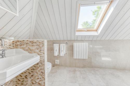 La salle de bains blanche est pourvue d'un lavabo et d'une fenêtre. dans l'établissement Château d'Avesnes - Le Castelet, à Avesnes-en-Bray