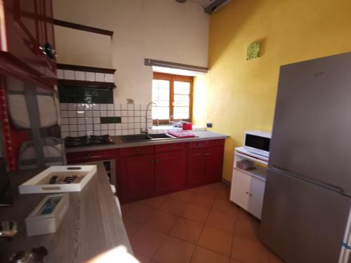 Il comprend une cuisine équipée de placards rouges et d'un réfrigérateur blanc. dans l'établissement Le gite de Coco, à Riquewihr