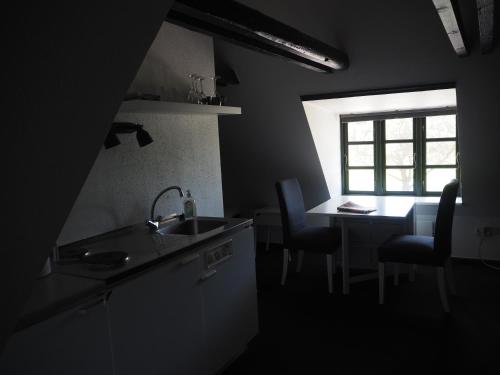 a kitchen with a sink and a table and a window at Blåvandshuk Golf Hostel in Blåvand