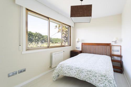 Habitación blanca con cama y ventana en Housingcoruña Apartamento Playa Miño 03, en Miño