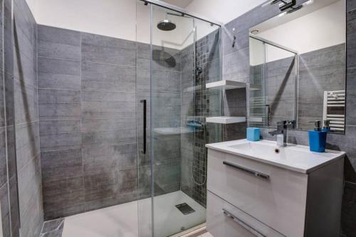 ein Bad mit einer Glasdusche und einem Waschbecken in der Unterkunft Appartement T3 classé***centre ville in Périgueux