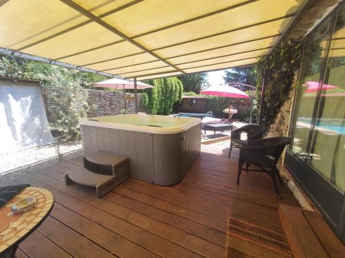 a patio with a hot tub on a deck at Le temps des pauses in Viviers