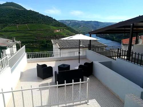 a patio with chairs and an umbrella on a balcony at Casa Rodrigues in Pinhão