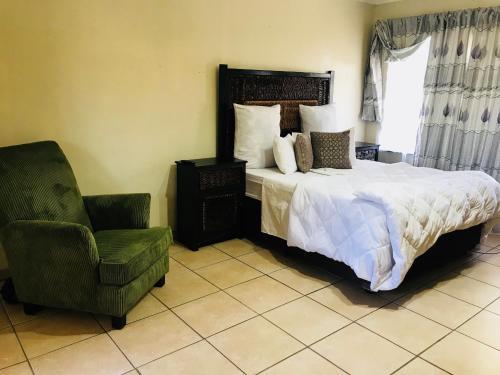 a bedroom with a large bed and a chair at Kaste Guesthouse Secunda in Secunda