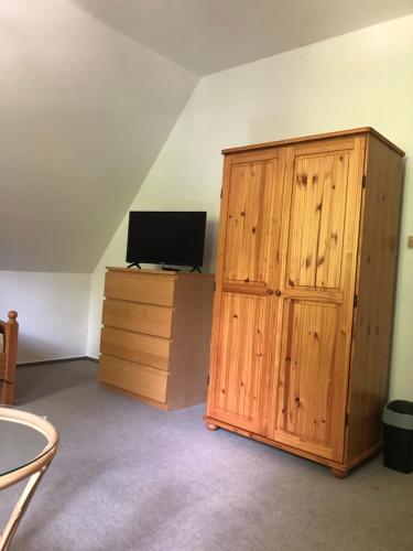 a room with a wooden cabinet and a television at Malá Svatá Hora - penzion & restaurace in Mníšek pod Brdy