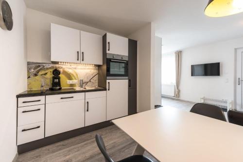 a kitchen with white cabinets and a table at Apart Hotel - Dillinger Schwabennest in Dillingen an der Donau