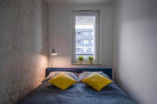 Un dormitorio con una cama con almohadas amarillas y una ventana en Star4You II Apartments, en Wroclaw