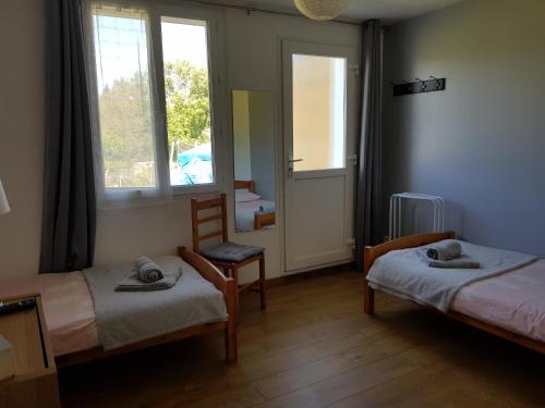 um quarto com duas camas e uma cadeira e uma janela em Les Trois Lions em Foix