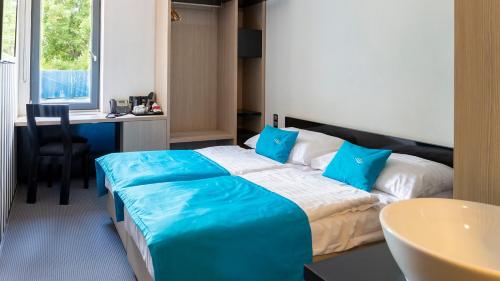a hotel room with a large bed with blue pillows at Hotel AquaCity Riverside in Poprad