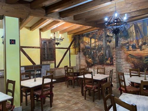 a restaurant with tables and chairs and a mural at Hotel Rural El Marqués in Saldaña