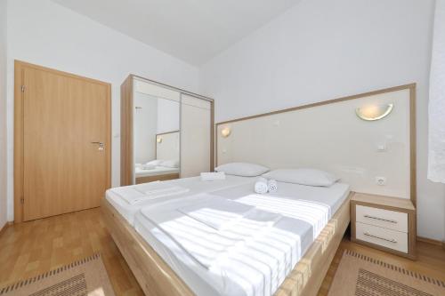 sypialnia z dużym białym łóżkiem z dużym lustrem w obiekcie Villa Rajna w mieście Starigrad-Paklenica