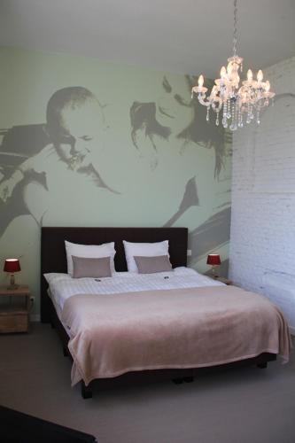 a bedroom with a large bed with a chandelier at B&B Amuse-Couche in Hasselt