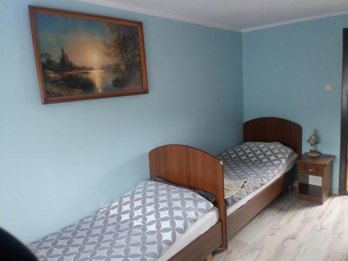 a bedroom with two beds and a painting on the wall at Pod Sarenką in Szczawnica