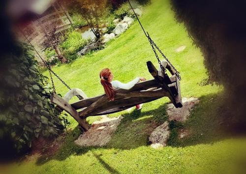a woman sitting on a swing in a park at Apartma Alpski vrt in Vojsko