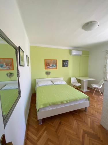 a bedroom with a green bed and a table at Apartmani Denona Centar in Novalja