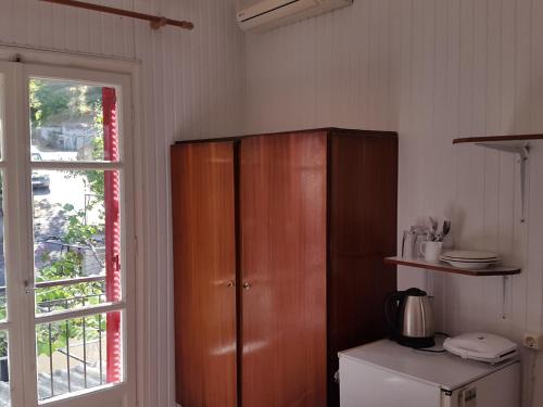 a kitchen with a wooden cabinet next to a window at faliraki apartments in Benitses